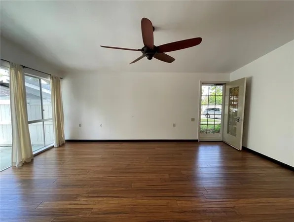 an empty room with wooden floor and windows