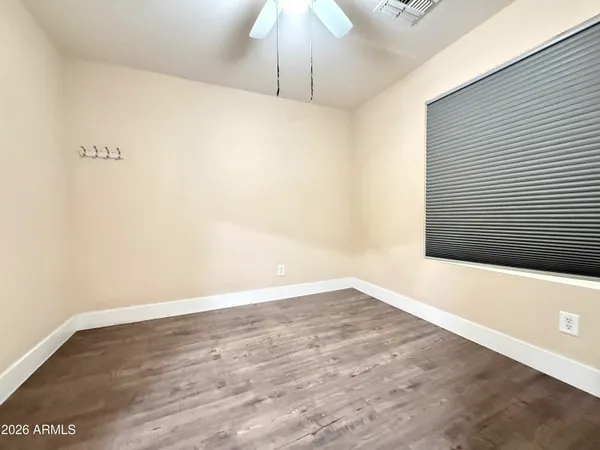 a view of an empty room with wooden floor and ceiling fan