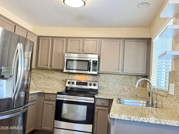 a kitchen with granite countertop a sink stove and refrigerator