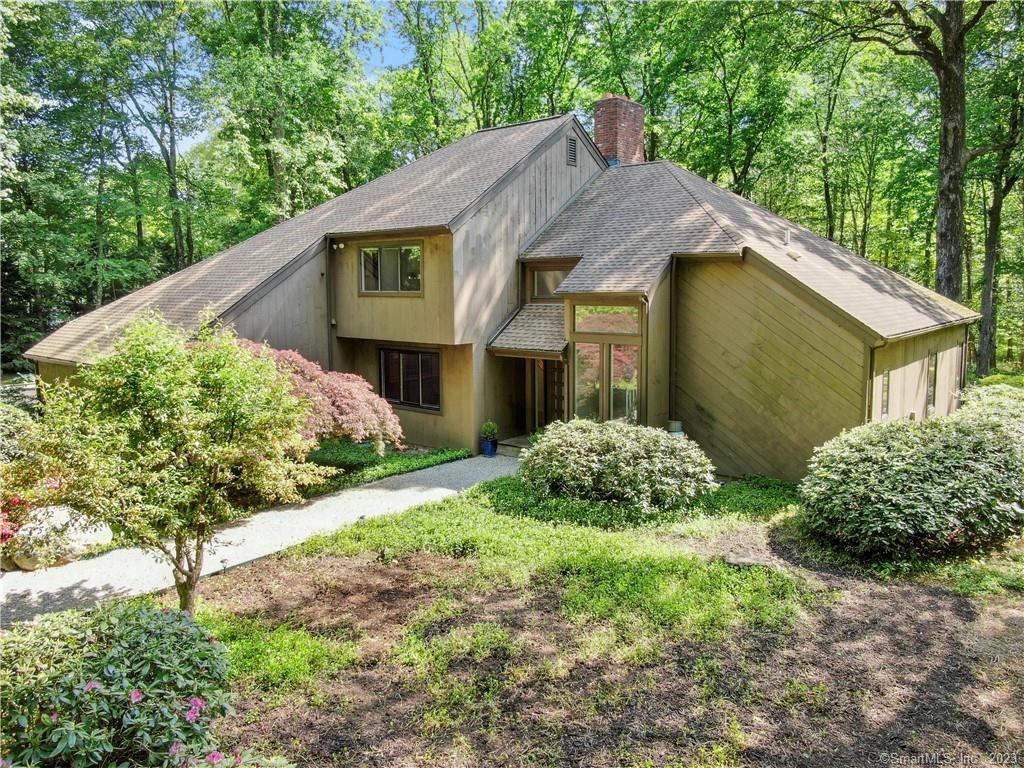 a view of a house with a small yard plants and large tree