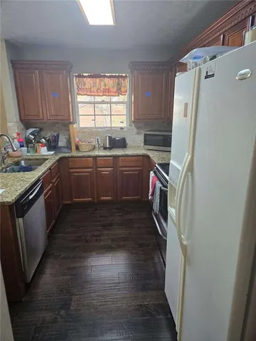 a kitchen with granite countertop a refrigerator and a sink