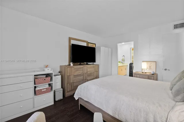 a bedroom with a bed and flat tv screen on the dresser