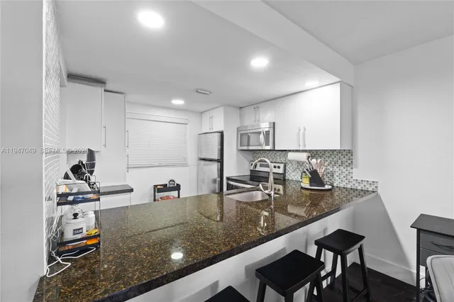 a kitchen with stainless steel appliances granite countertop a sink a stove and white cabinets