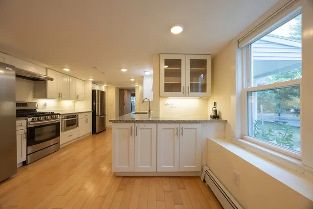 a large kitchen with stainless steel appliances granite countertop a stove and a large window
