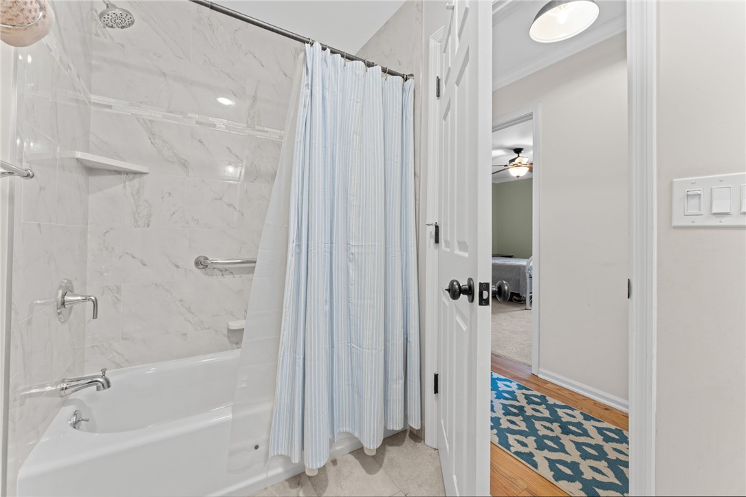 200 Poore Road Piedmont, SC 29673 - Photo 26 of 44 This bathroom features a sleek tub with tiled shower walls, offering a clean and functional design.