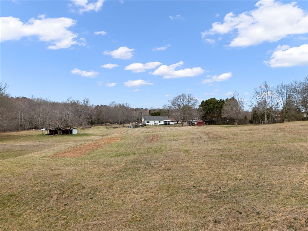 200 Poore Road Piedmont, SC 29673 - Photo 41 of 44 Expansive natural landscape with verdant grasses and distant structures under a blue sky.