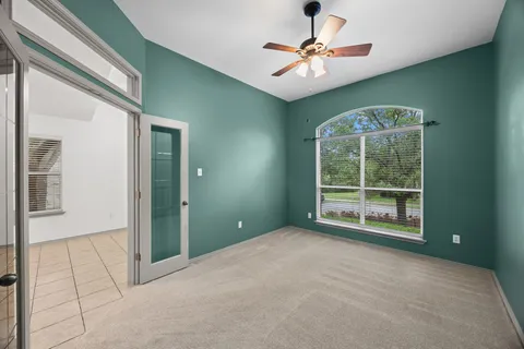 an empty room with chandelier fan and windows