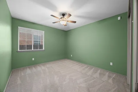 a view of an empty room with window and fan