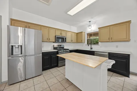 a kitchen with granite countertop a refrigerator stove top oven and sink