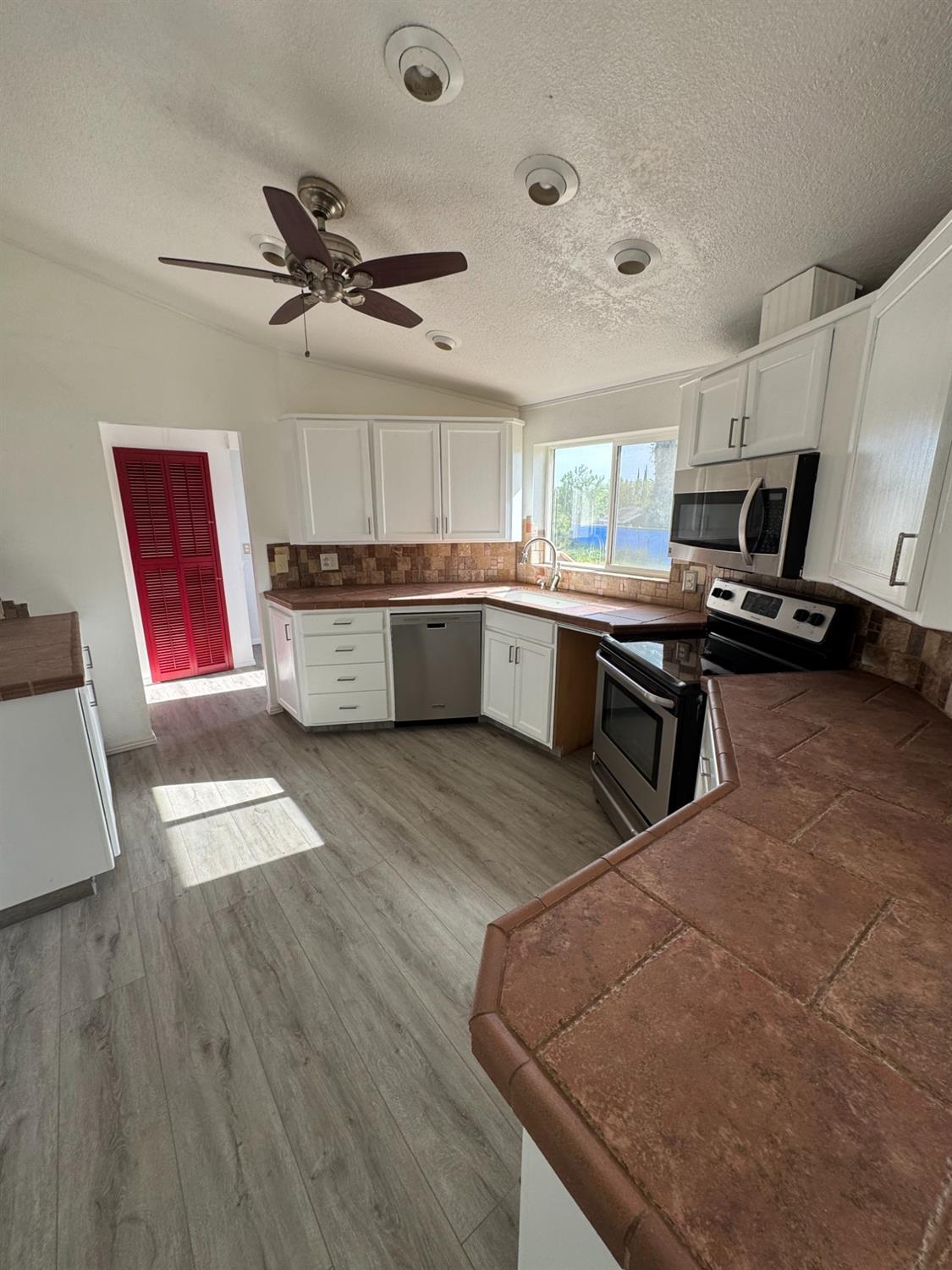 28640 Ward Street Madera, CA 93638 - Photo 12 of 31 a kitchen with stainless steel appliances granite countertop a sink dishwasher stove and microwave with wooden floor
