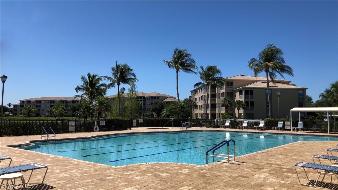 14111 Brant Point Circle, Unit 2201 Fort Myers, FL 33919 - Photo 28 of 30 a view of a swimming pool with a lawn chairs under an umbrella