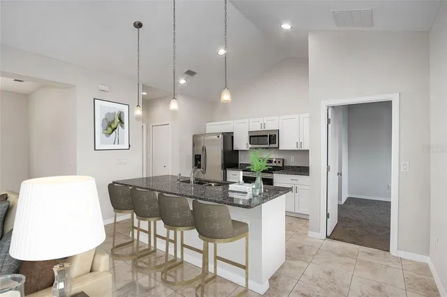 a kitchen with stainless steel appliances kitchen island granite countertop a refrigerator a stove a microwave oven a dining table and chairs with wooden floor