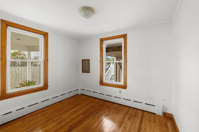 a view of a kitchen and an empty room with wooden floor