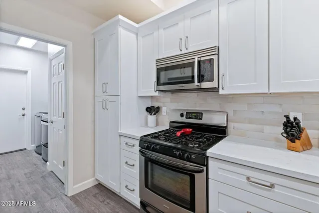 a kitchen with white cabinets and stainless steel appliances