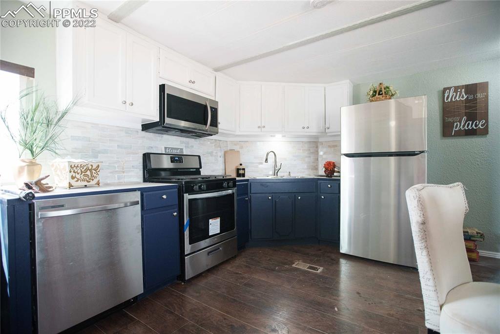 6605 Lauppe Road Yoder, CO 80864 - Photo 4 of 38 a kitchen with stainless steel appliances granite countertop a refrigerator stove a sink dishwasher and microwave with wooden floor