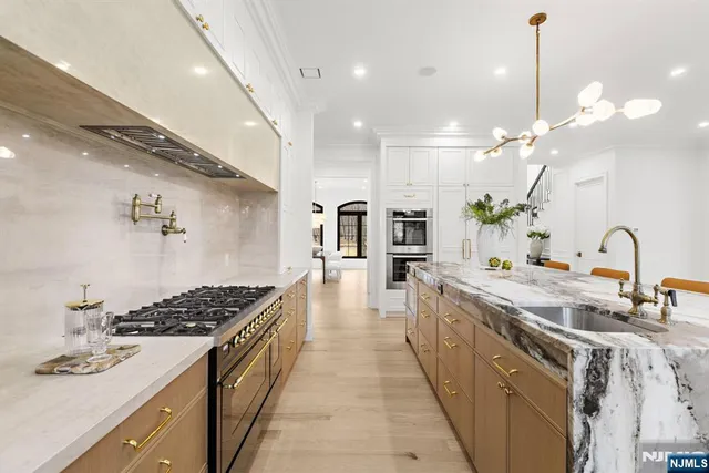 a large kitchen with stainless steel appliances a stove a sink a oven and a large island with wooden floor