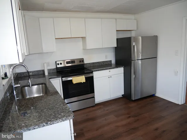 a kitchen with granite countertop a refrigerator stove and sink