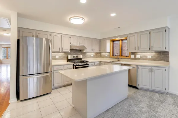 a kitchen with white cabinets stainless steel appliances and a window