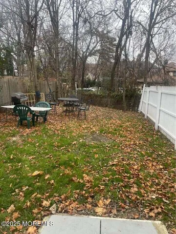 a view of backyard with table and chairs and wooden fence