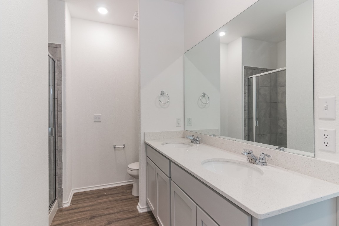 231 Rioja Kyle, TX 78640 - Photo 18 of 29 Bathroom featuring a shower stall, double vanity, dark wood-type flooring, and recessed lighting