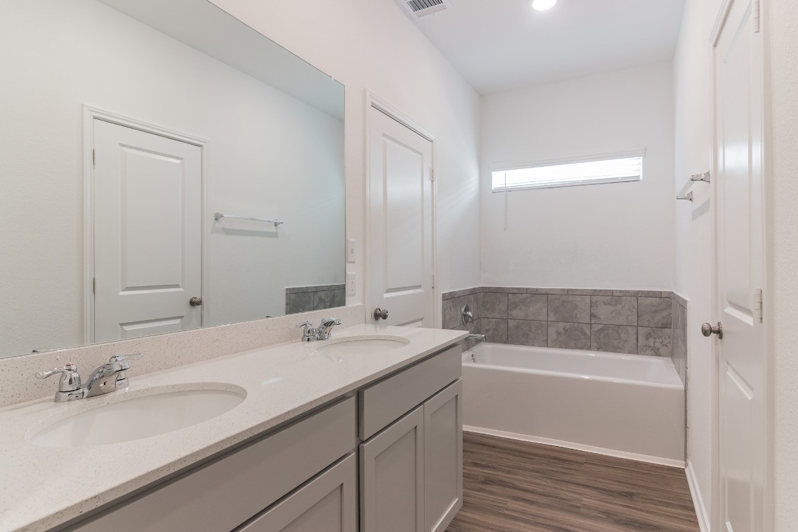 231 Rioja Kyle, TX 78640 - Photo 19 of 29 Bathroom featuring double vanity, dark wood finished floors, and a bath