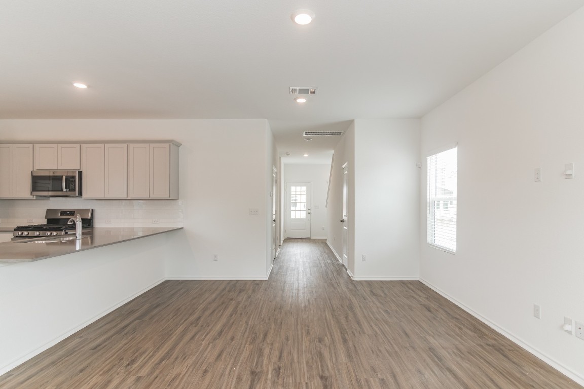 231 Rioja Kyle, TX 78640 - Photo 6 of 29 Kitchen featuring dark wood-style floors, stainless steel appliances, gray cabinetry, recessed lighting, and a peninsula
