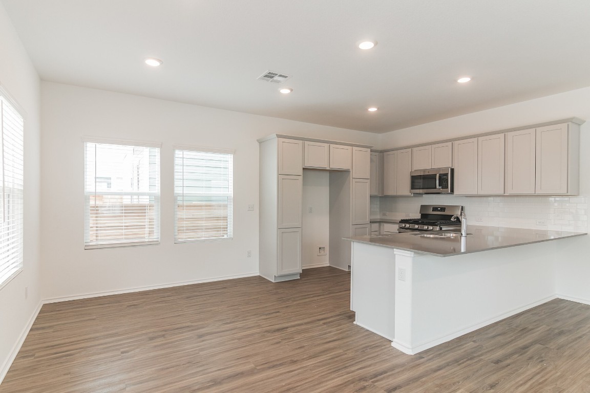 231 Rioja Kyle, TX 78640 - Photo 8 of 29 Kitchen featuring a peninsula, stainless steel appliances, dark wood-style flooring, recessed lighting, and decorative backsplash