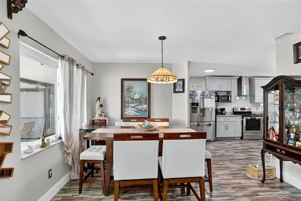 a room with stainless steel appliances kitchen island granite countertop a dining table chairs and a refrigerator