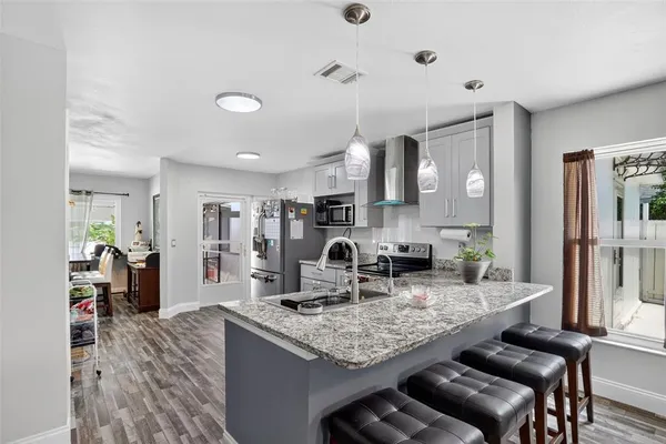 a kitchen with granite countertop kitchen island stainless steel appliances a sink stove and refrigerator