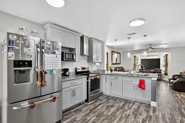 a kitchen that has a refrigerator a stove top oven a sink dishwasher and white cabinets with wooden floor