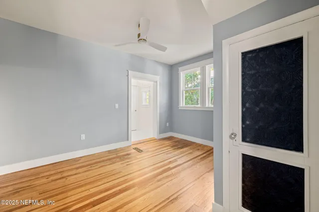 a view of an empty room with wooden floor and a window
