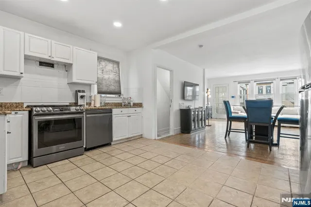 a kitchen with stainless steel appliances a stove a sink dishwasher and white cabinets with wooden floor