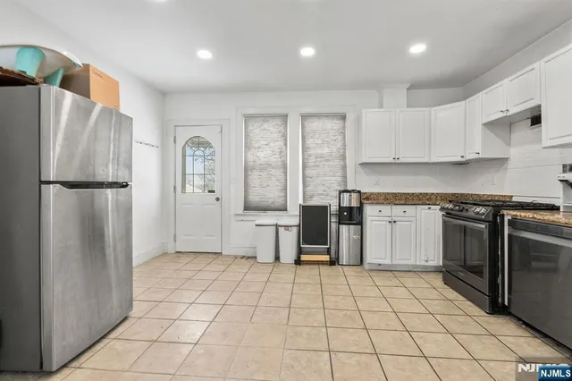a kitchen with a stove a refrigerator and white cabinets