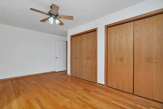 an empty room with wooden floor closet chandelier fan and windows