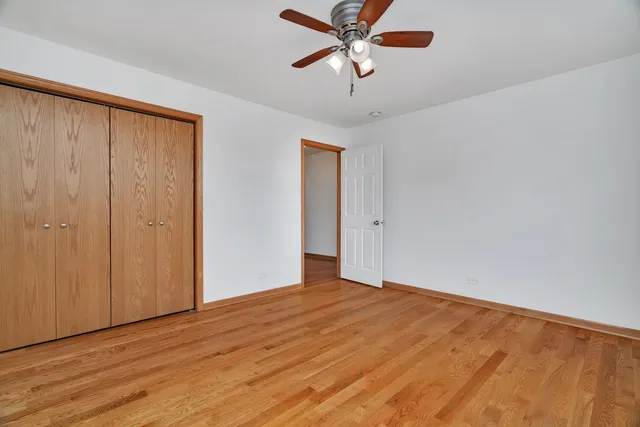 an empty room with wooden floor closet and ceiling fan
