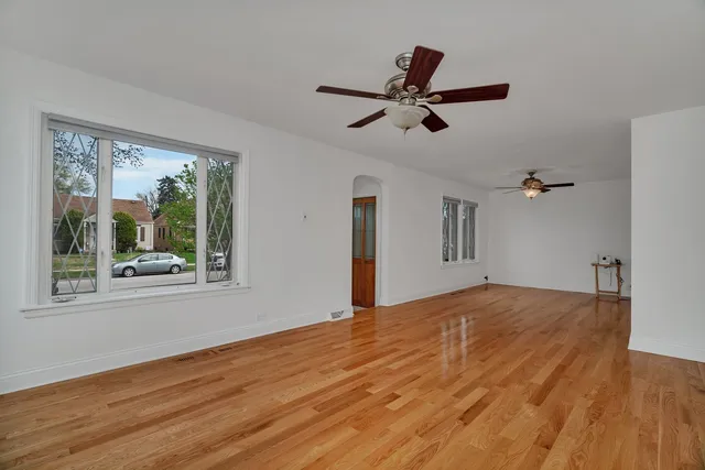 a view of empty room with wooden floor and fan