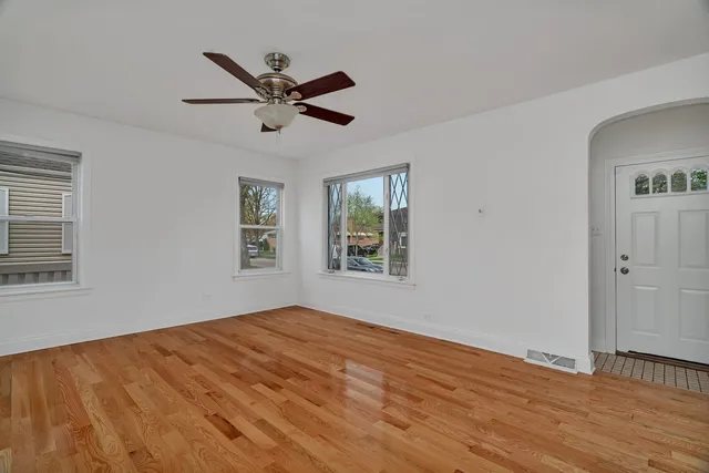 a view of empty room with wooden floor and fan