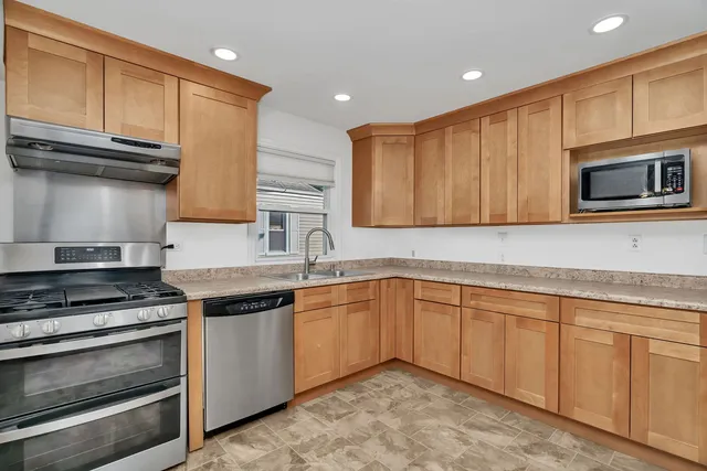 a kitchen with granite countertop wooden cabinets and a stove top oven