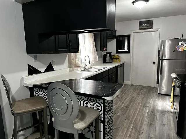 a kitchen with stainless steel appliances a table chairs in it and wooden floor