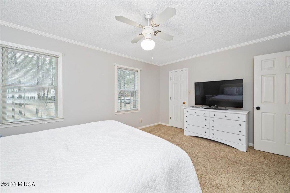 347 Castlegate Road Macon, GA 31210 - Photo 26 of 34 a bedroom with a bed a flat screen tv and a chandelier