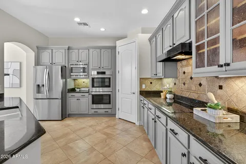 a kitchen with stainless steel appliances granite countertop a sink refrigerator and cabinets