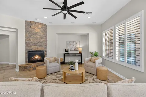 a living room with furniture a ceiling fan a fireplace and a window
