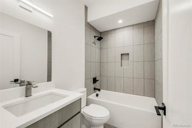 a bathroom with a bathtub shower sink vanity mirror and toilet