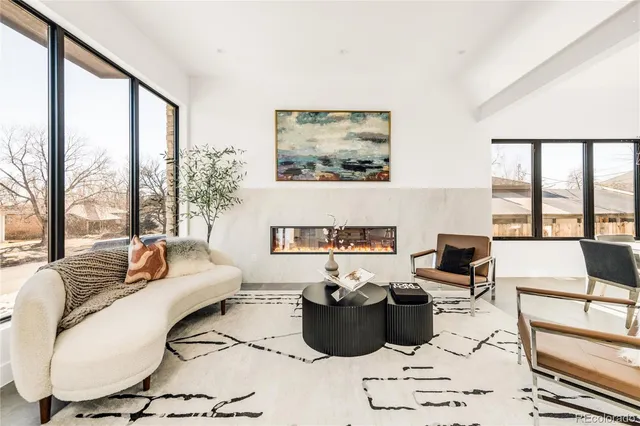 a living room with furniture fireplace and floor to ceiling windows