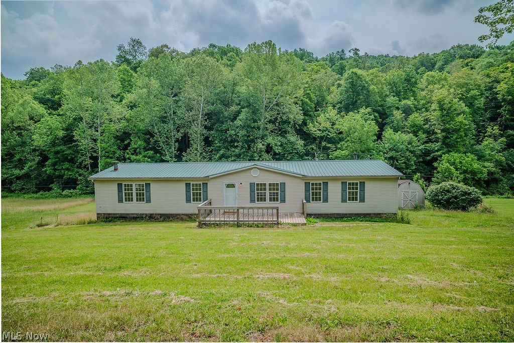 967 Buck Run Road Mineral Wells, WV 26150 - Photo 44 of 50 Cream-colored home featuring a green metal roof, a front porch with wooden railings, and green window shutters