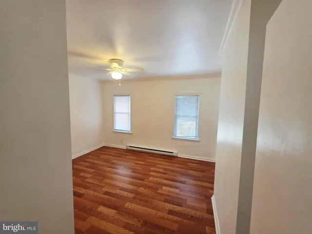 a view of an empty room with window and a ceiling fan