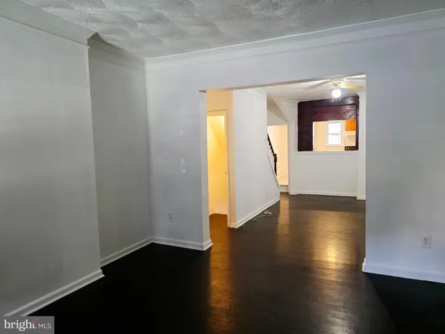 an empty room with wooden floor and windows with curtains