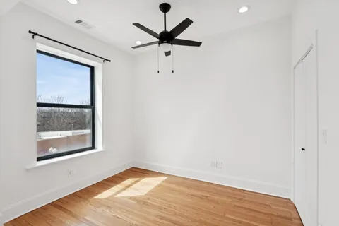 a view of empty room with wooden floor and ceiling fan