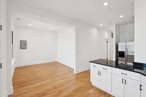 a kitchen with granite countertop white cabinets and wooden floor
