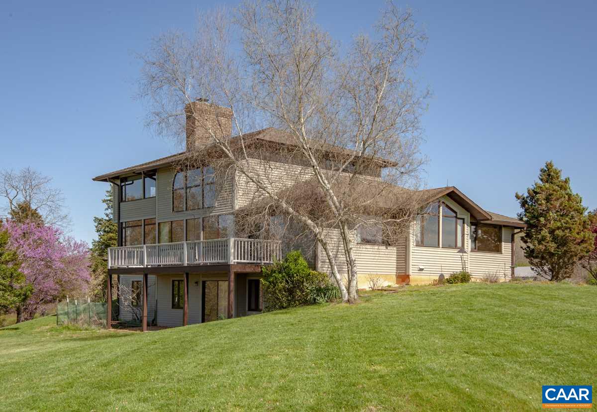 a view of a big house with a big yard and large trees